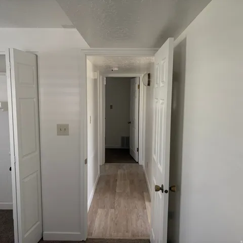 Hallway featuring a textured ceiling and light wood-style flooring