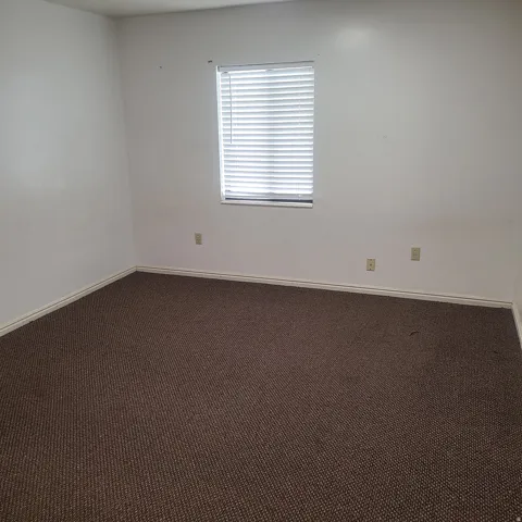 Unfurnished room with dark colored carpet and baseboards