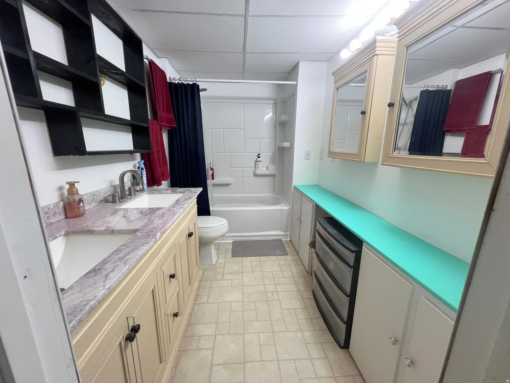 Bathroom with double vanity, a drop ceiling, and shower / bathtub combination with curtain