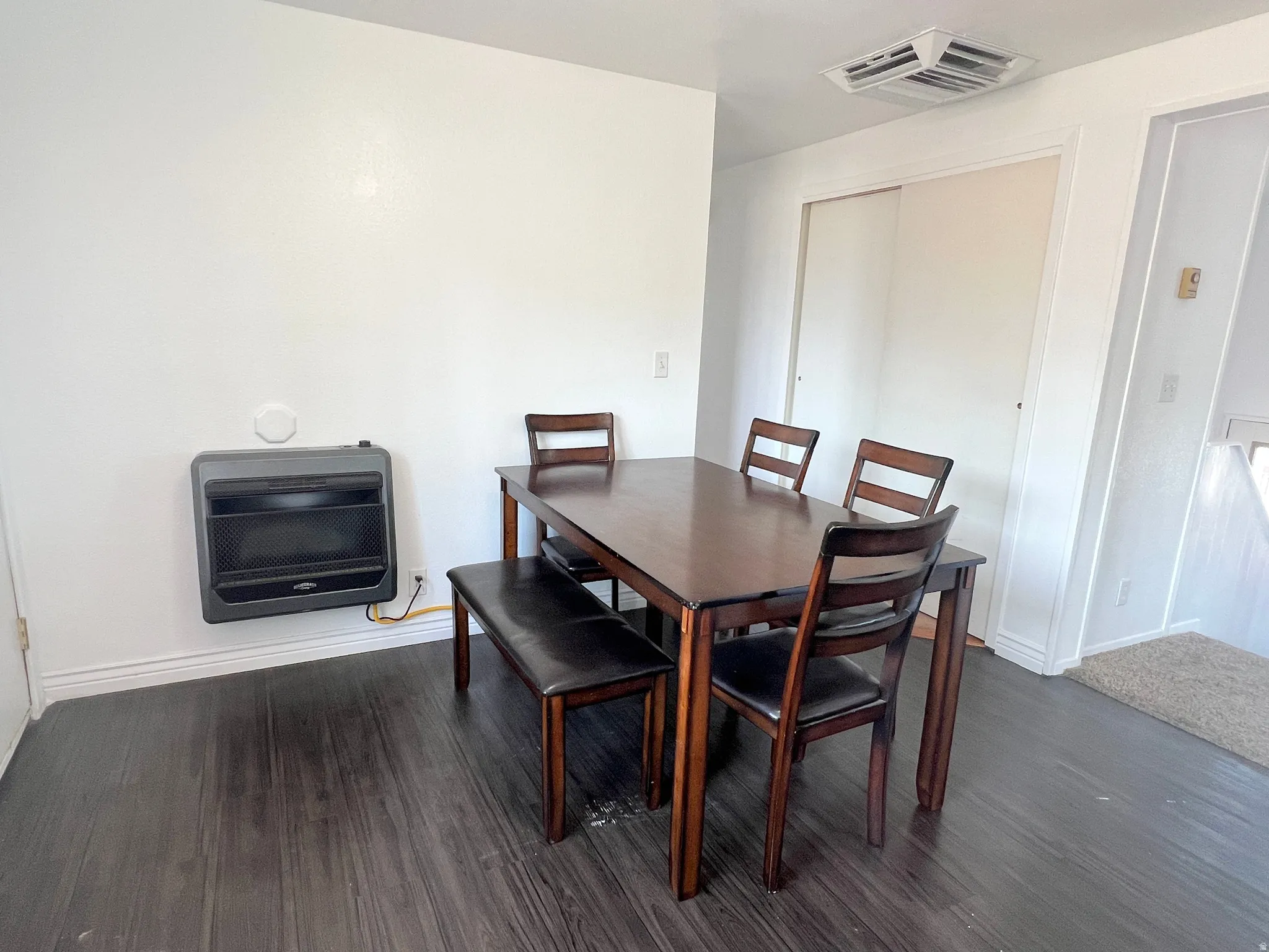 Dining area featuring dark wood-style floors and heating unit
