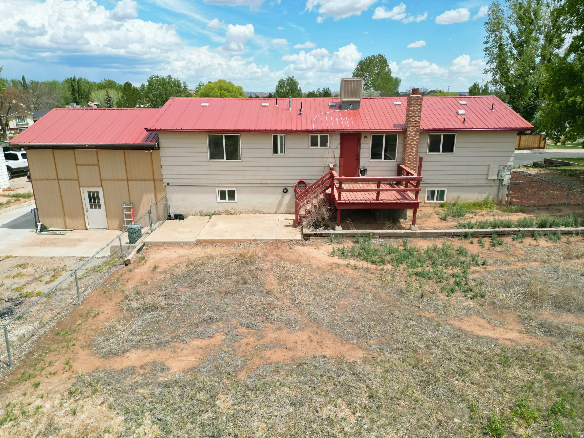 Rear view of property with a metal roof, a chimney, a deck, and a patio area