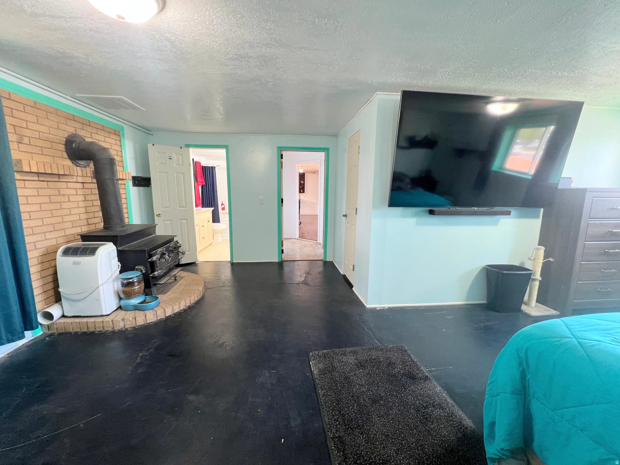 bedroom/Living area with a textured ceiling and a wood stove
