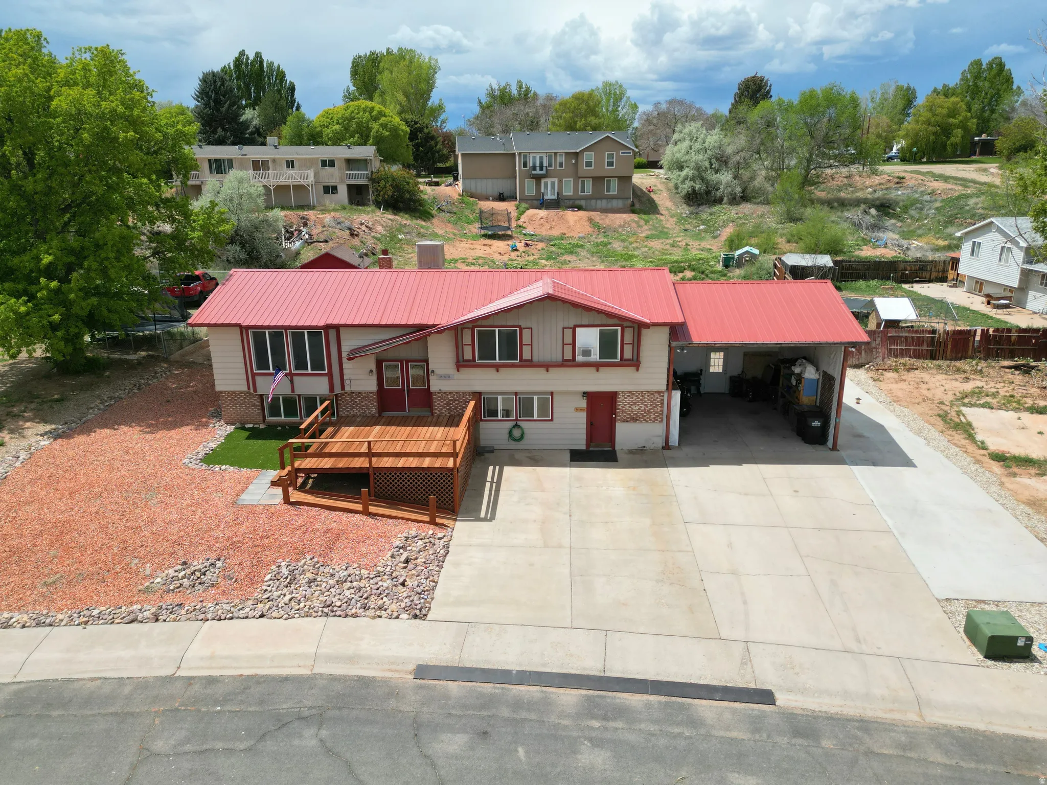 View of front of property with an attached carport, a metal roof, a deck, concrete driveway, and brick, siding