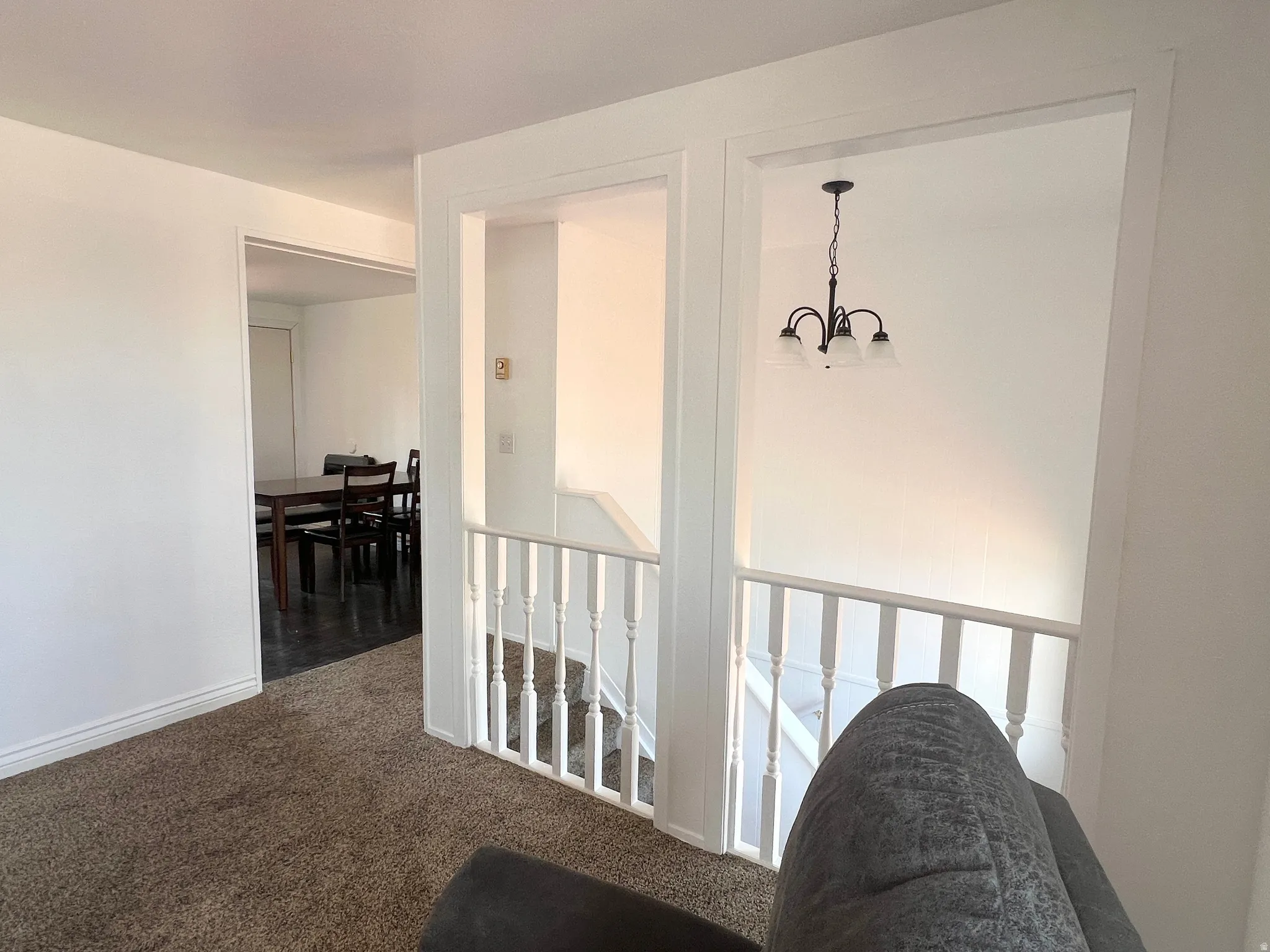 Hall with dark colored flooring carpet and hanging lights