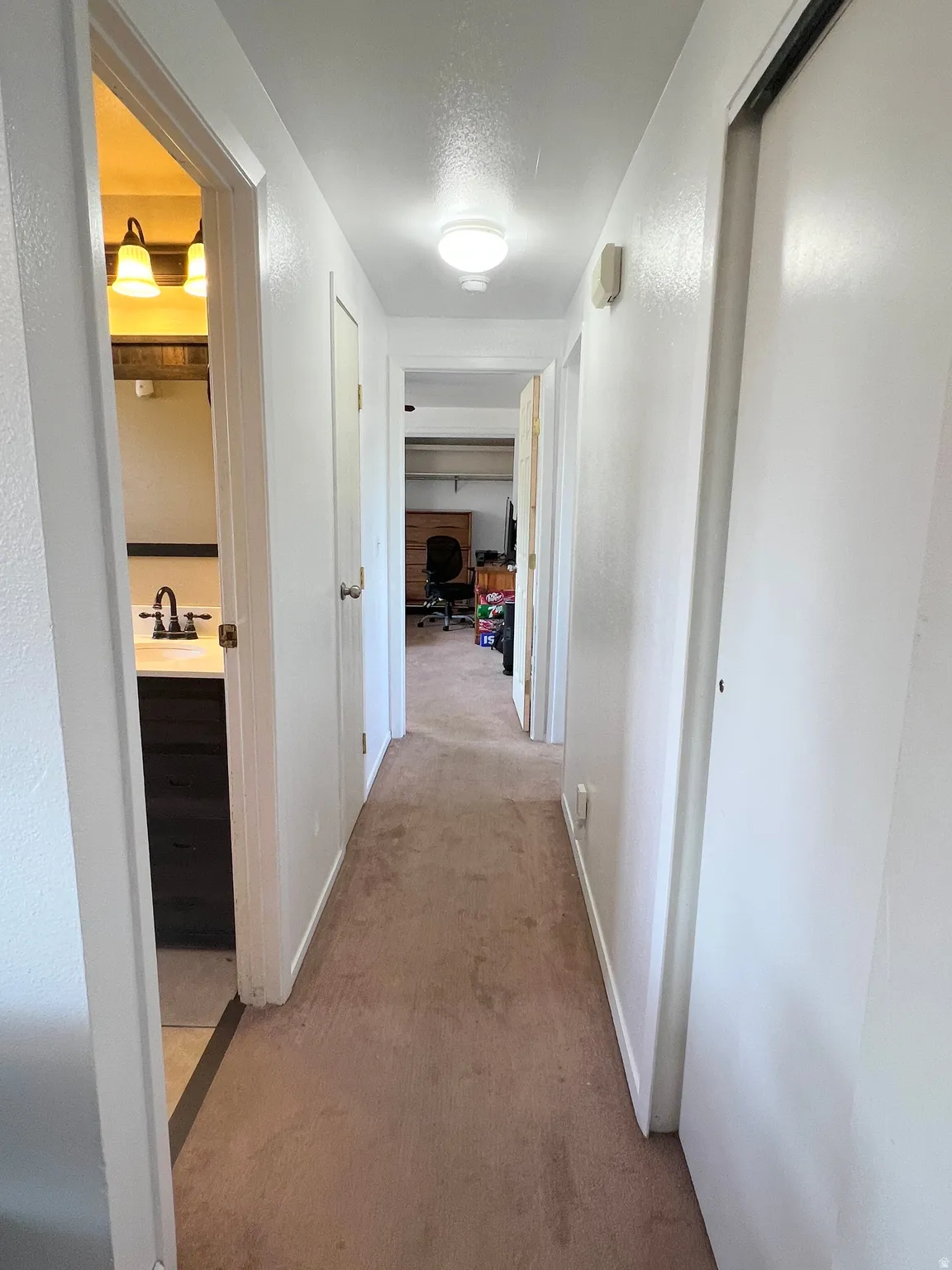 Corridor featuring light colored carpet and a textured ceiling