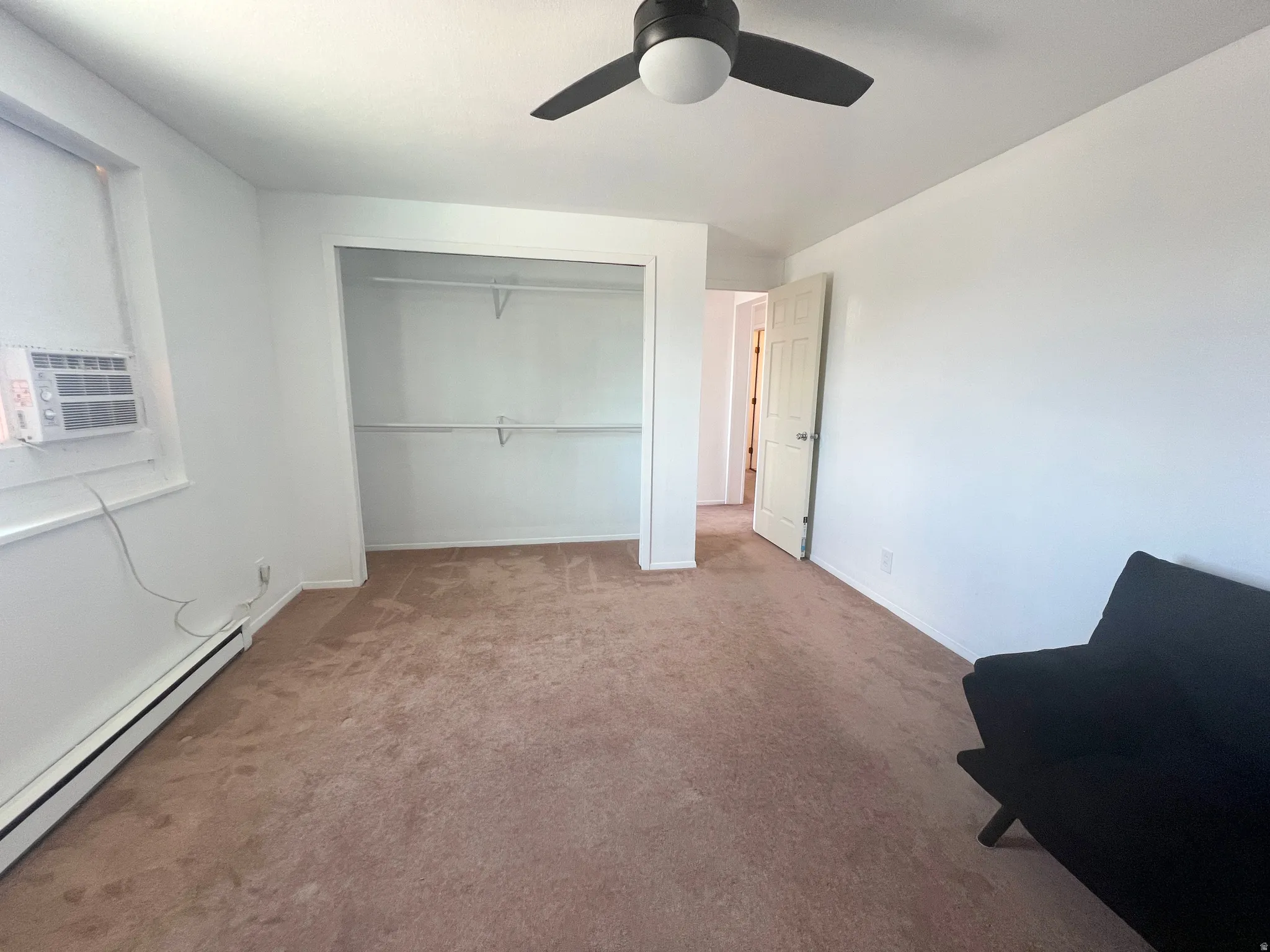 Carpeted bedroom with baseboard heating, a closet, a ceiling fan, and cooling unit