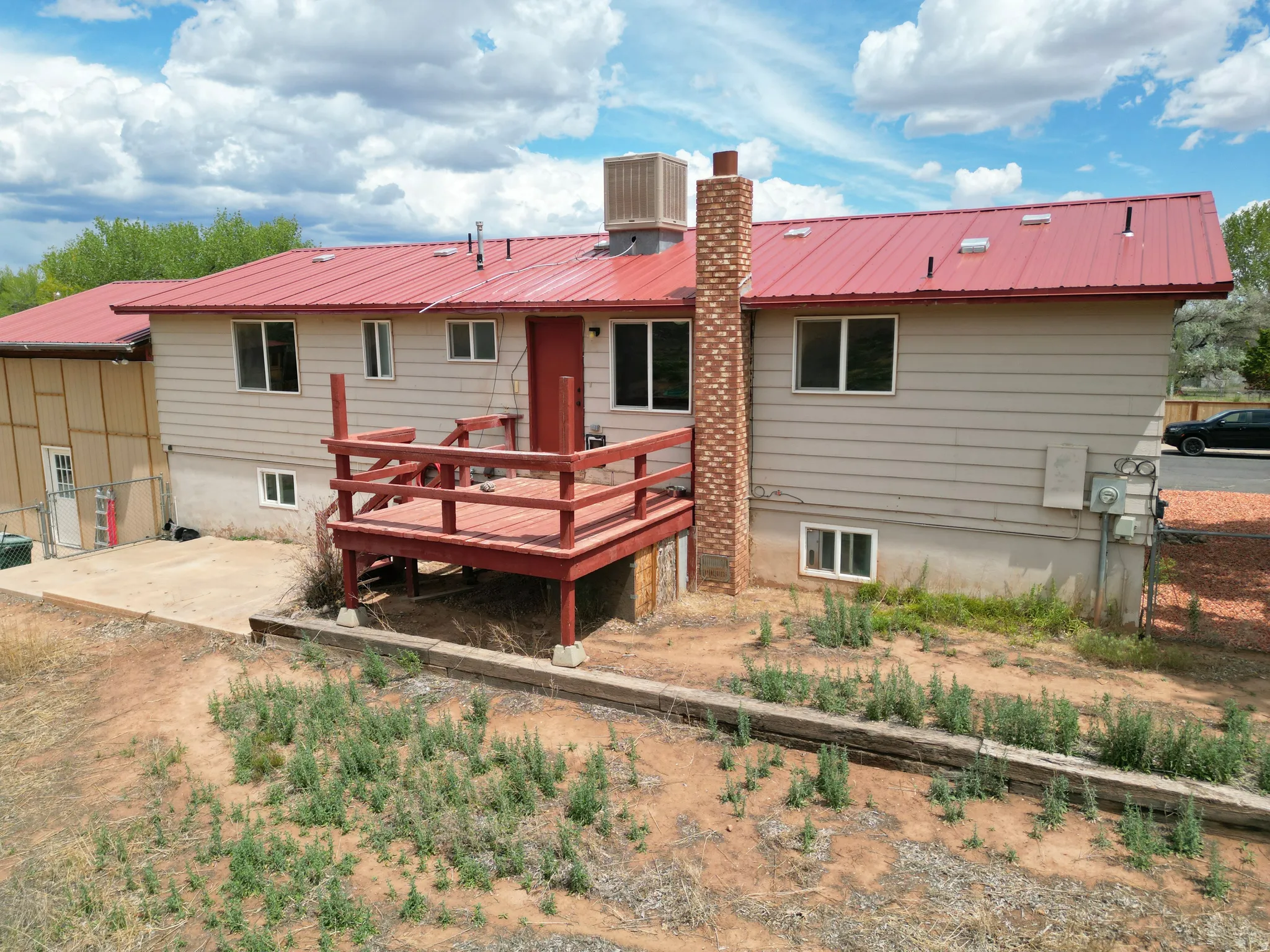 Back of property featuring a metal roof, a wooden deck, and a chimney