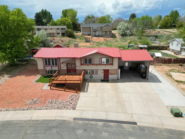 View of front of property with an attached carport, a metal roof, a deck, concrete driveway, and brick, siding