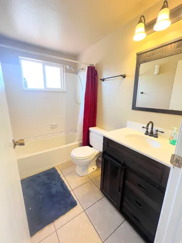 Full bath with vanity, shower / bath combo, and light tile patterned floors