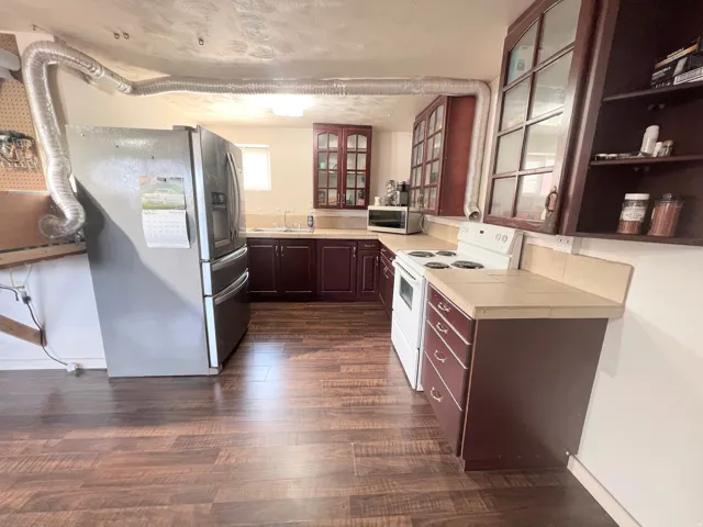 2nd Kitchen featuring stainless steel appliances, tile countertops, glass insert cabinets, and dark wood finished floors