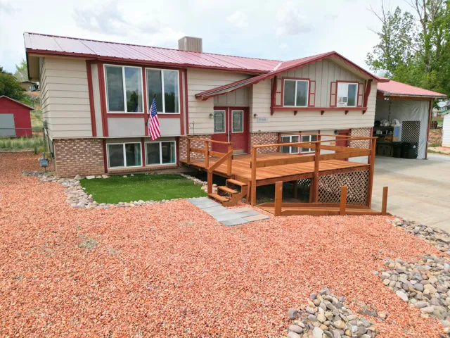 View of front of home featuring a deck, a metal roof, brick, siding, and concrete driveway