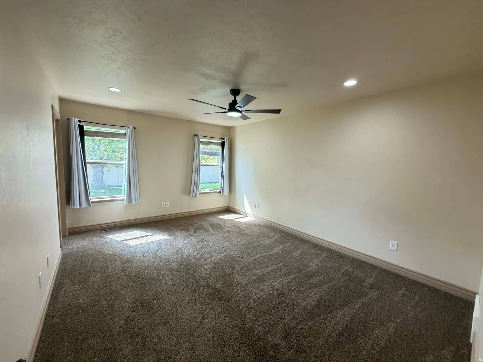Unfurnished room with dark colored carpet, recessed lighting, and a ceiling fan