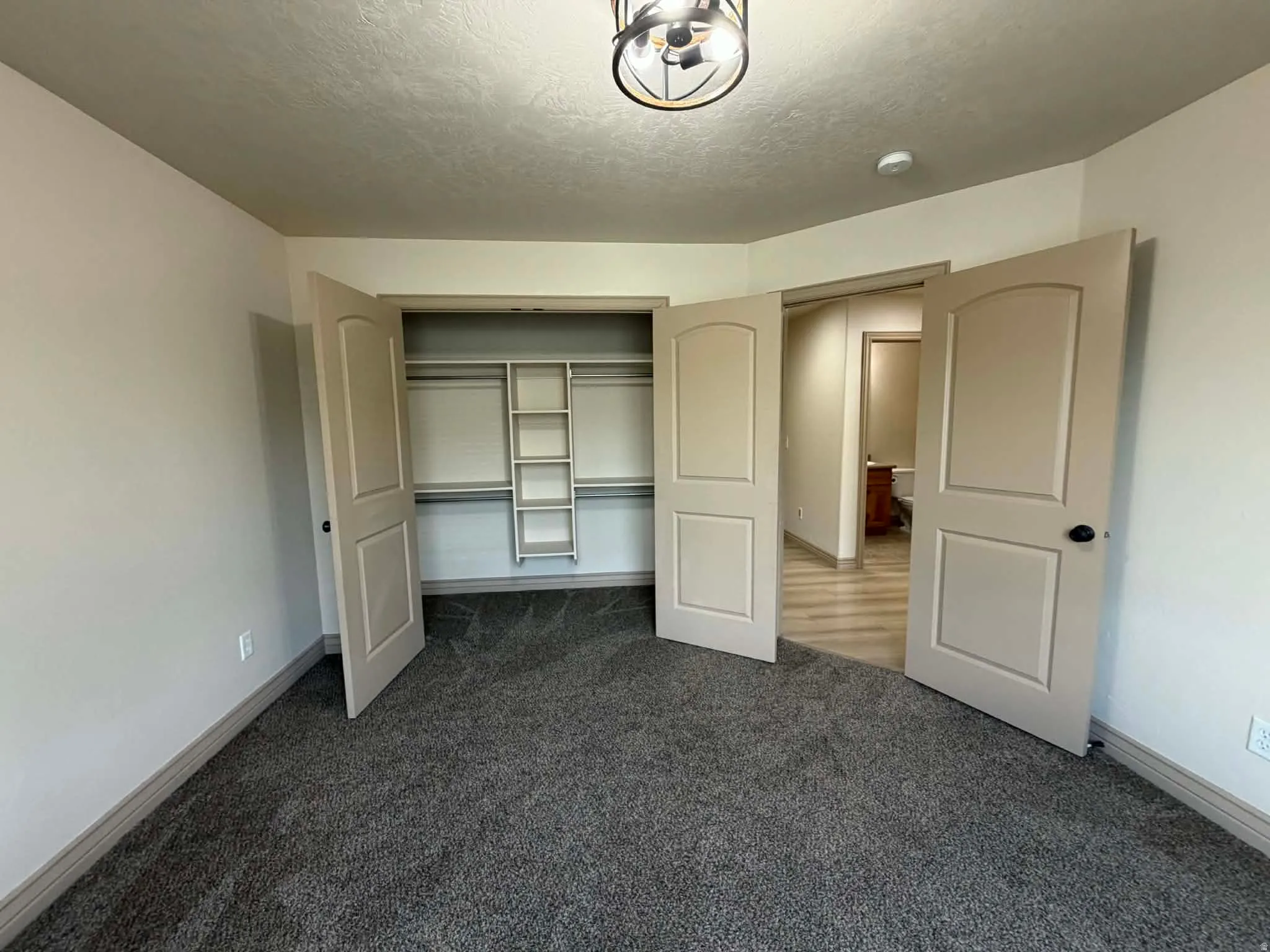 Unfurnished bedroom featuring dark carpet, a closet, and a textured ceiling