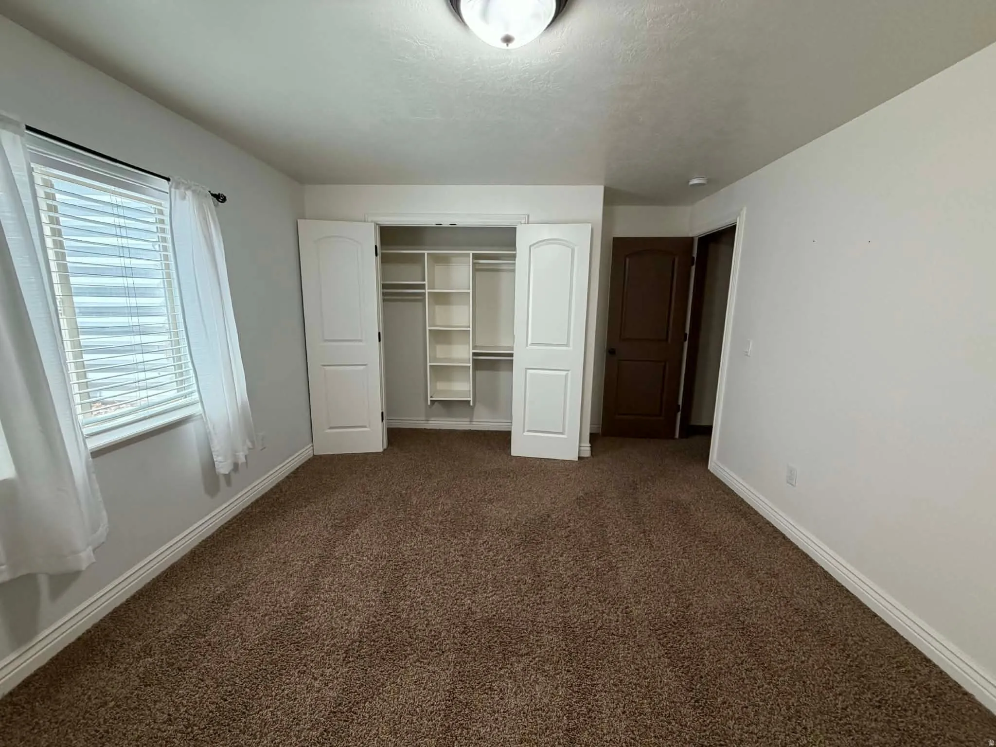 Unfurnished bedroom featuring dark colored carpet and a closet