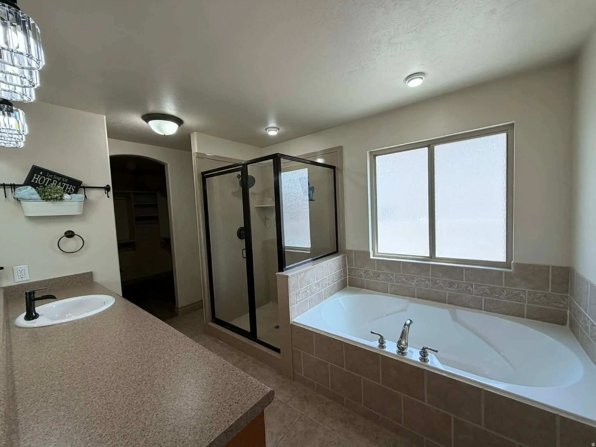 Bathroom with vanity, a walk in closet, a shower stall, a bath, and tile patterned flooring