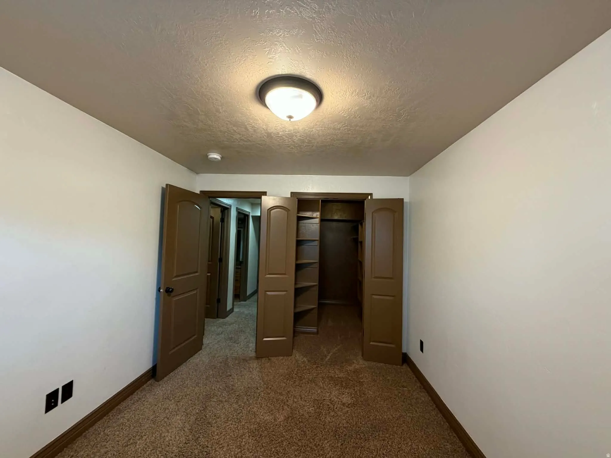 Unfurnished bedroom with a closet, a textured ceiling, and dark colored carpet