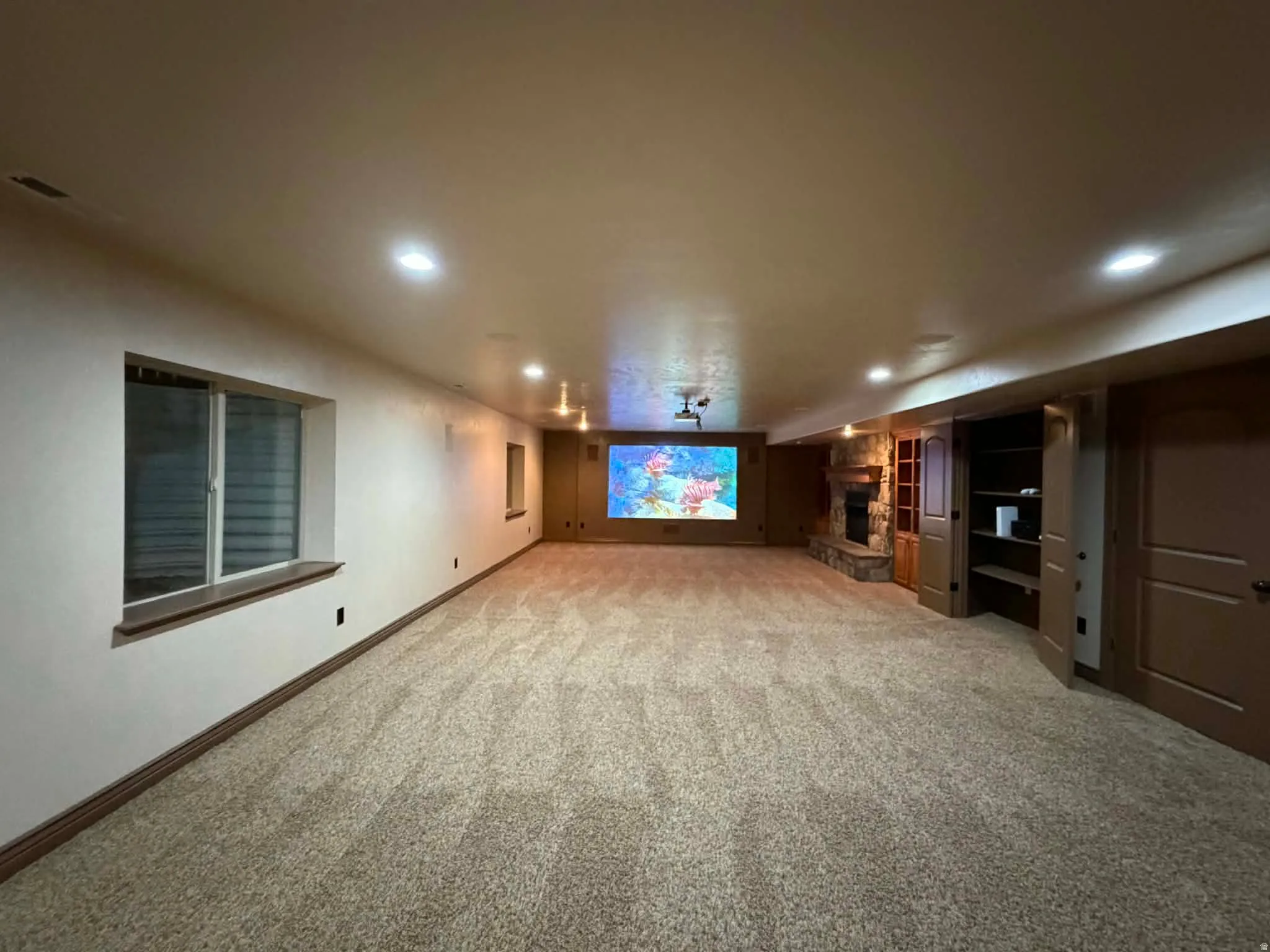 Finished below grade area with a fireplace, light colored carpet, and recessed lighting
