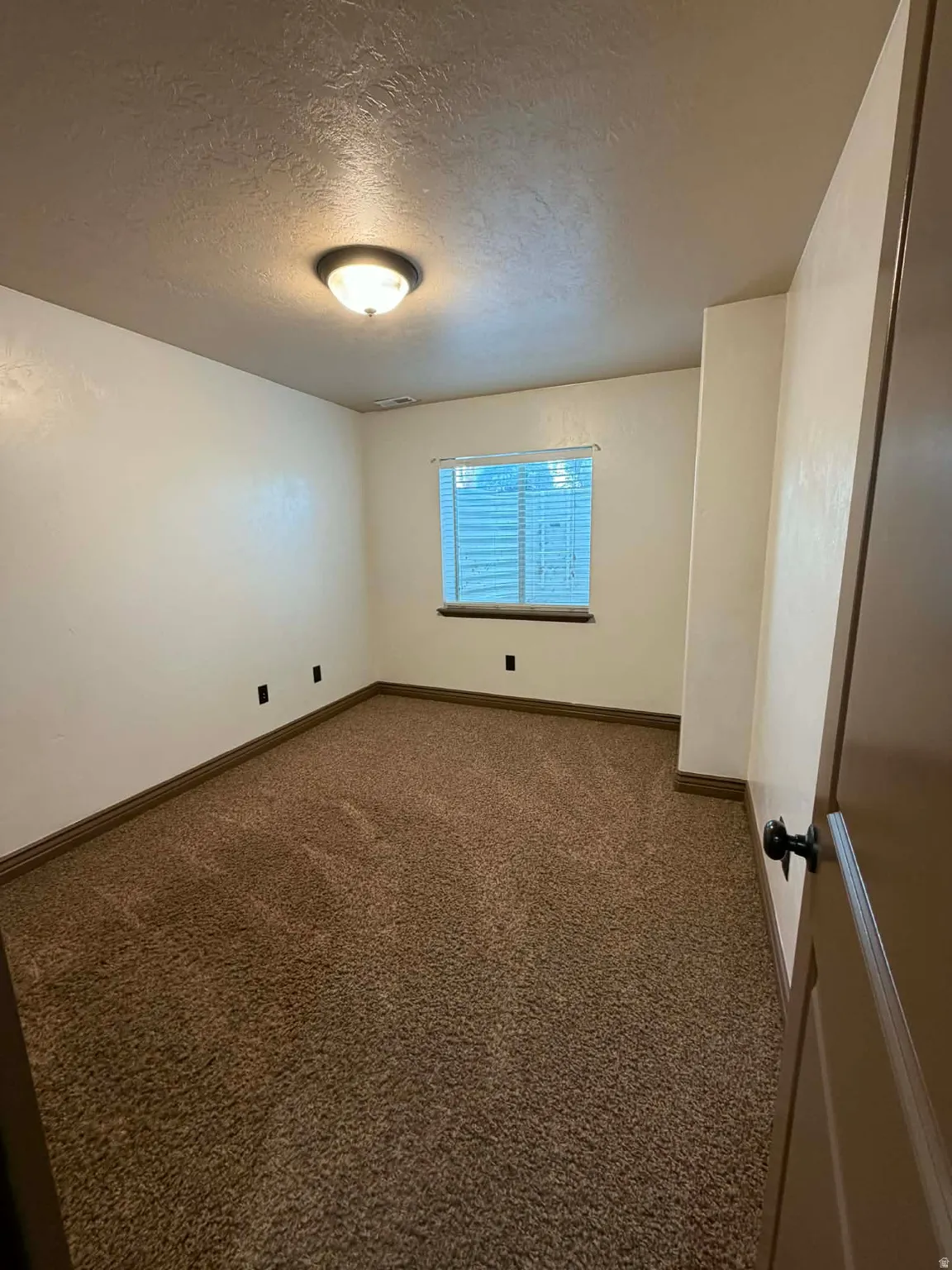 Spare room featuring dark colored carpet and a textured ceiling