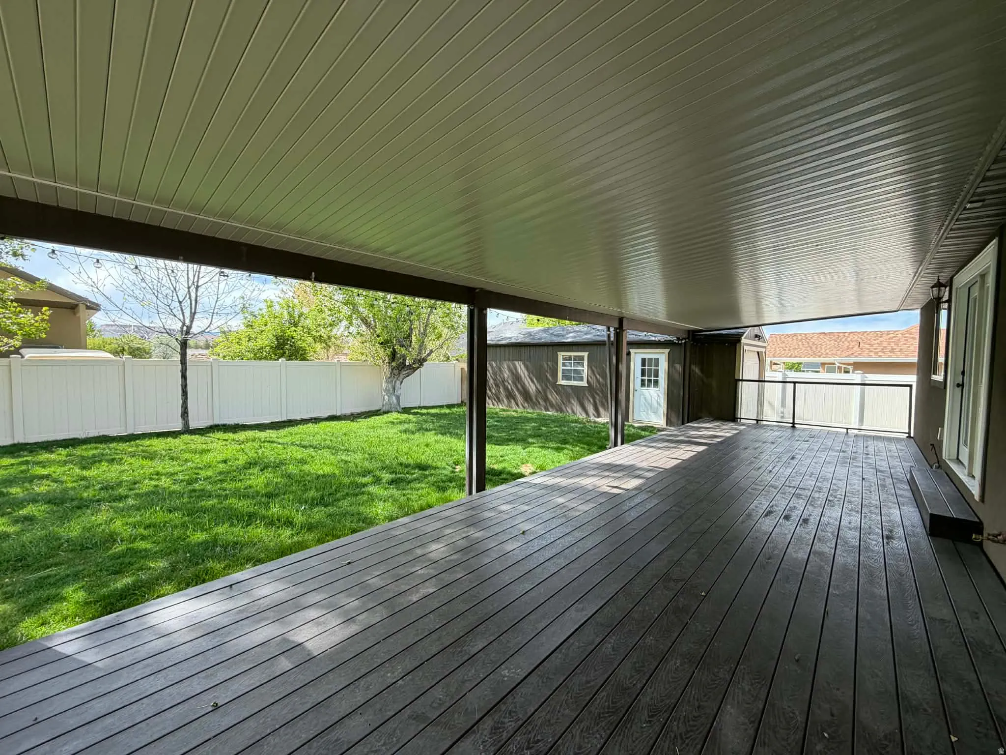 Wooden terrace with a fenced backyard and an outdoor structure