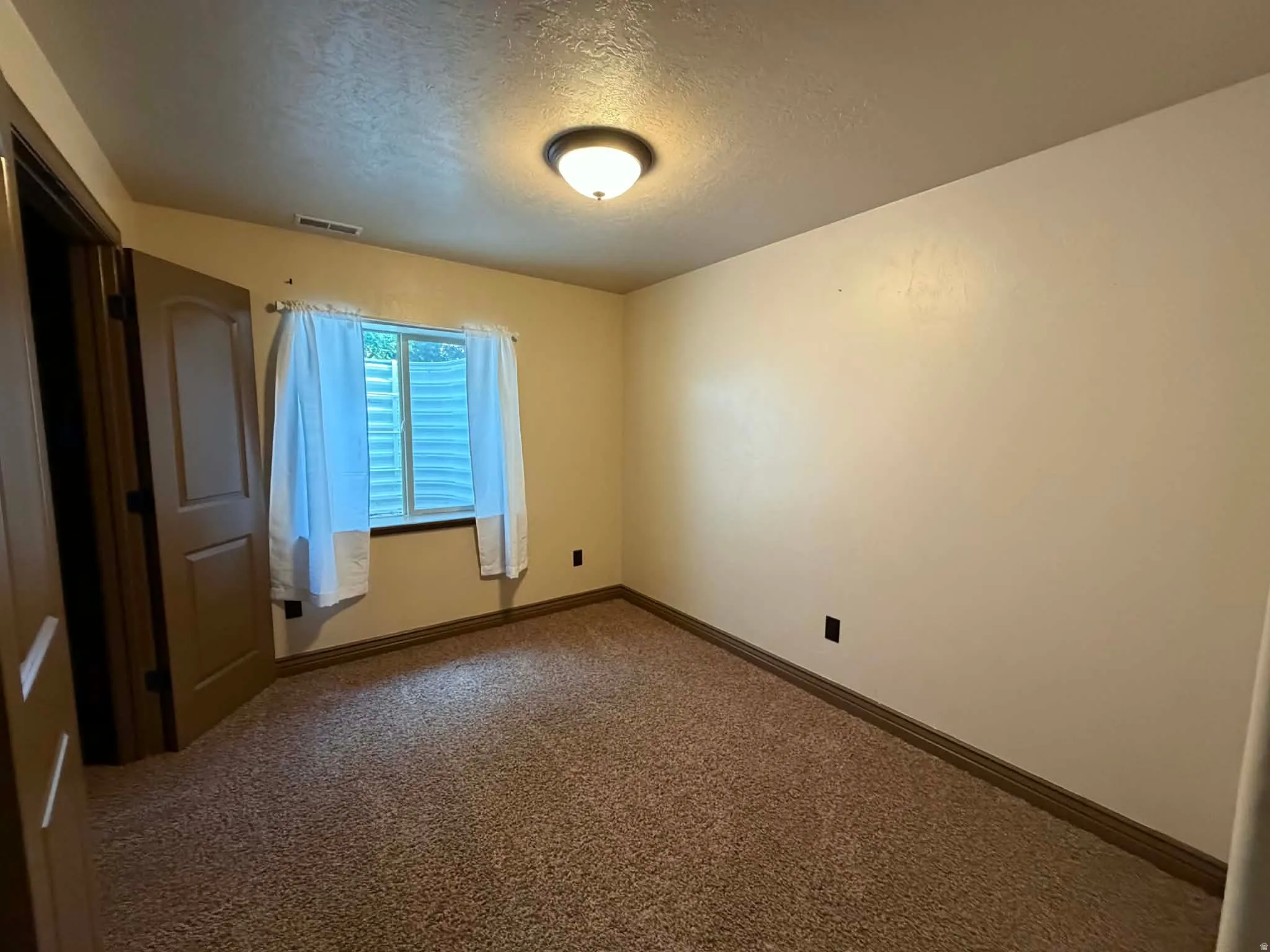 Unfurnished room with a textured ceiling and carpet flooring