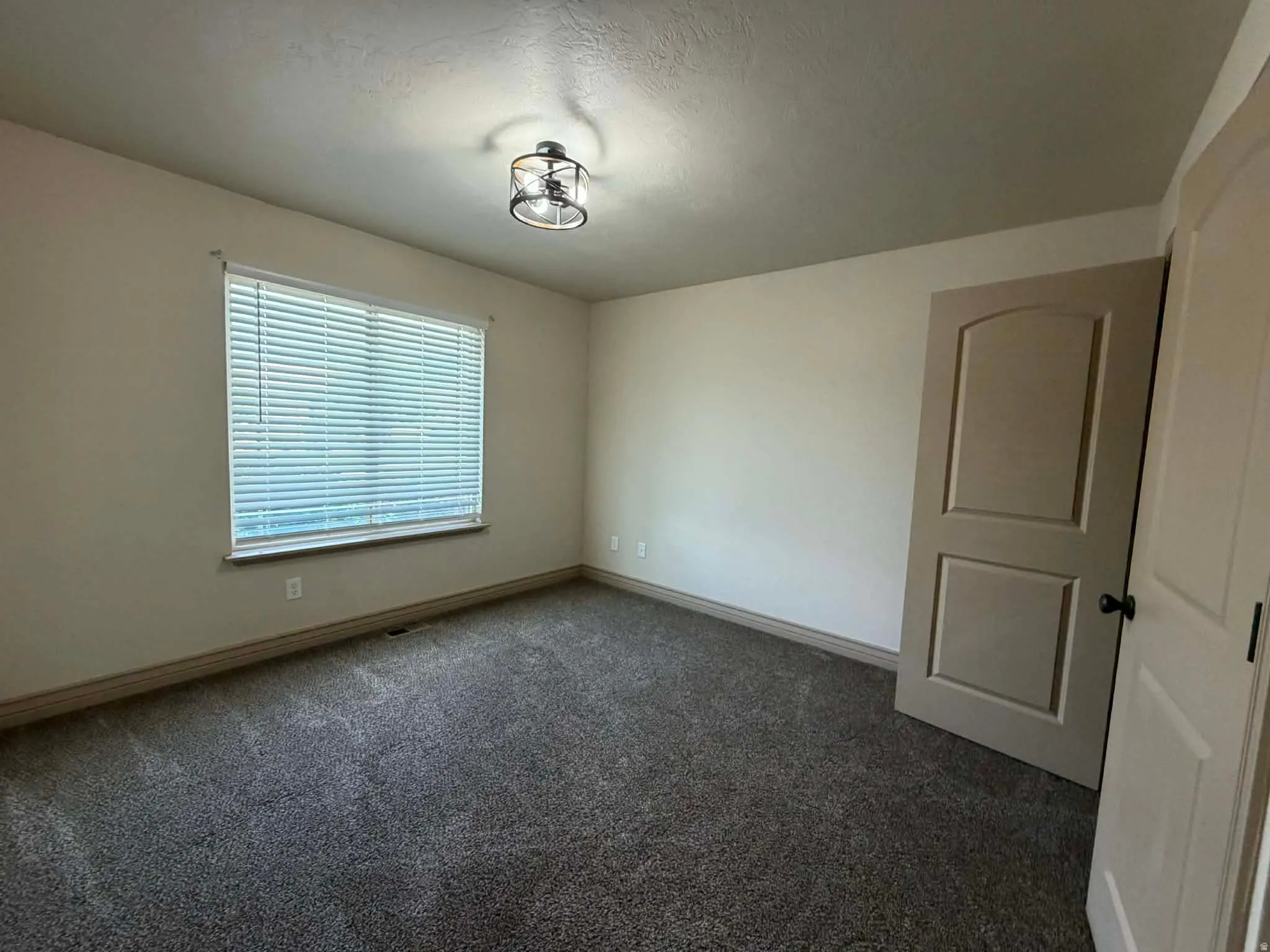 Spare room with dark carpet and a textured ceiling