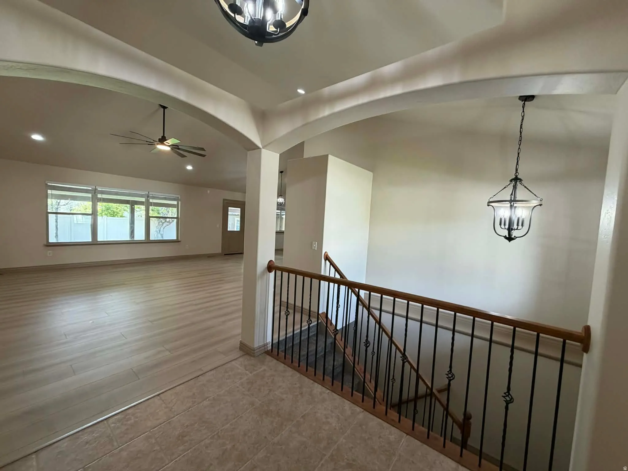 Hall featuring an upstairs landing, a chandelier, and arched walkways