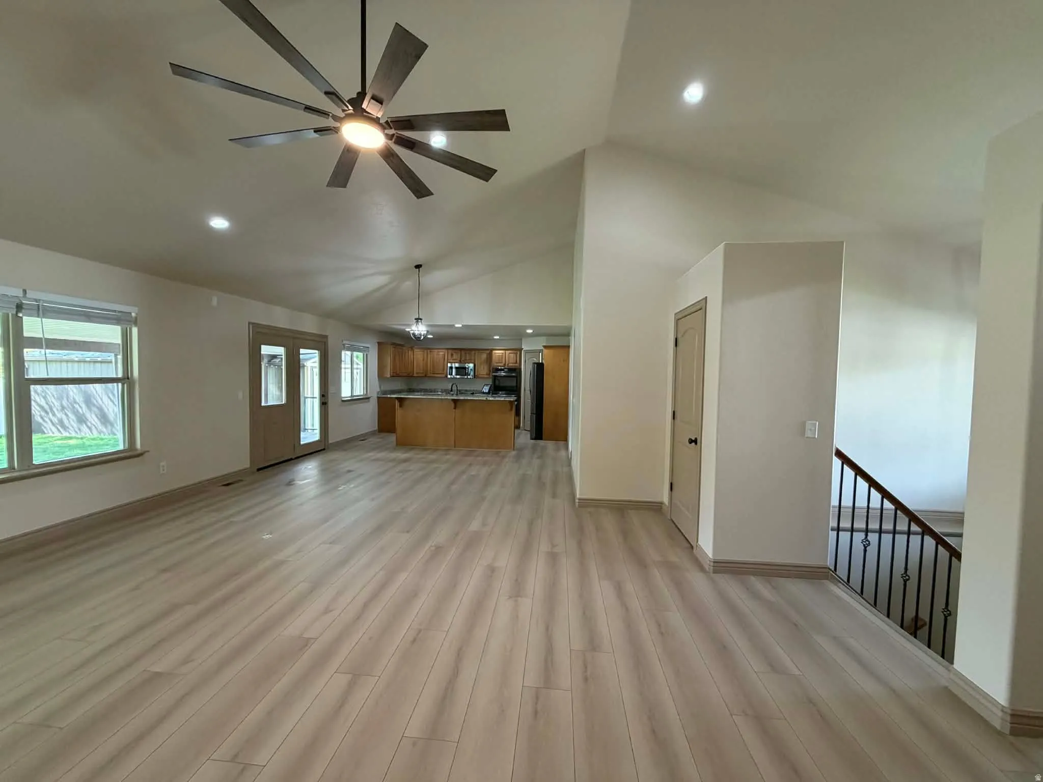 Unfurnished living room featuring ceiling fan, light wood-style flooring, vaulted ceiling, and recessed lighting