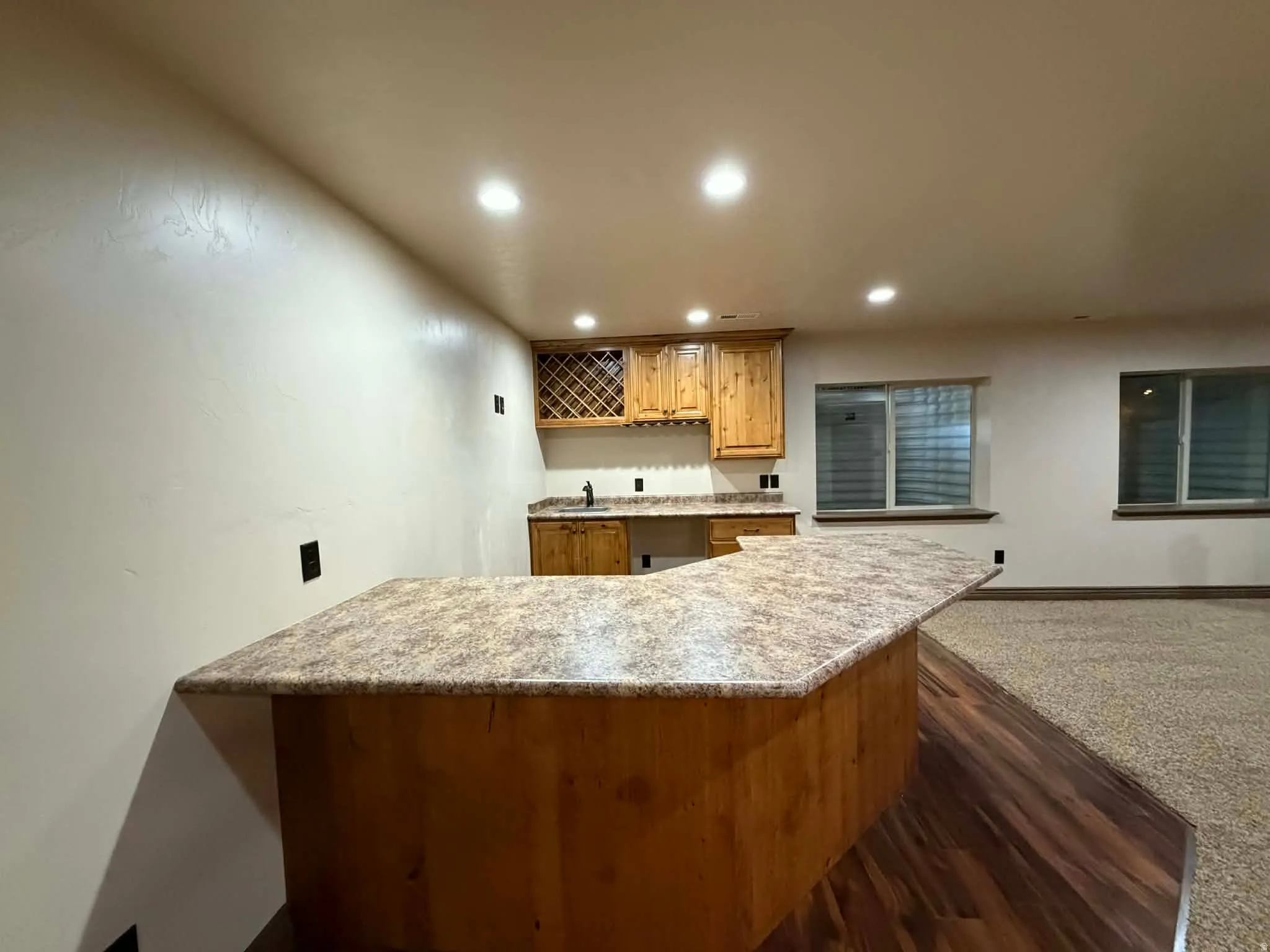 Kitchen with a peninsula, recessed lighting, dark wood-style floors, light stone countertops, and wood finish cabinetry