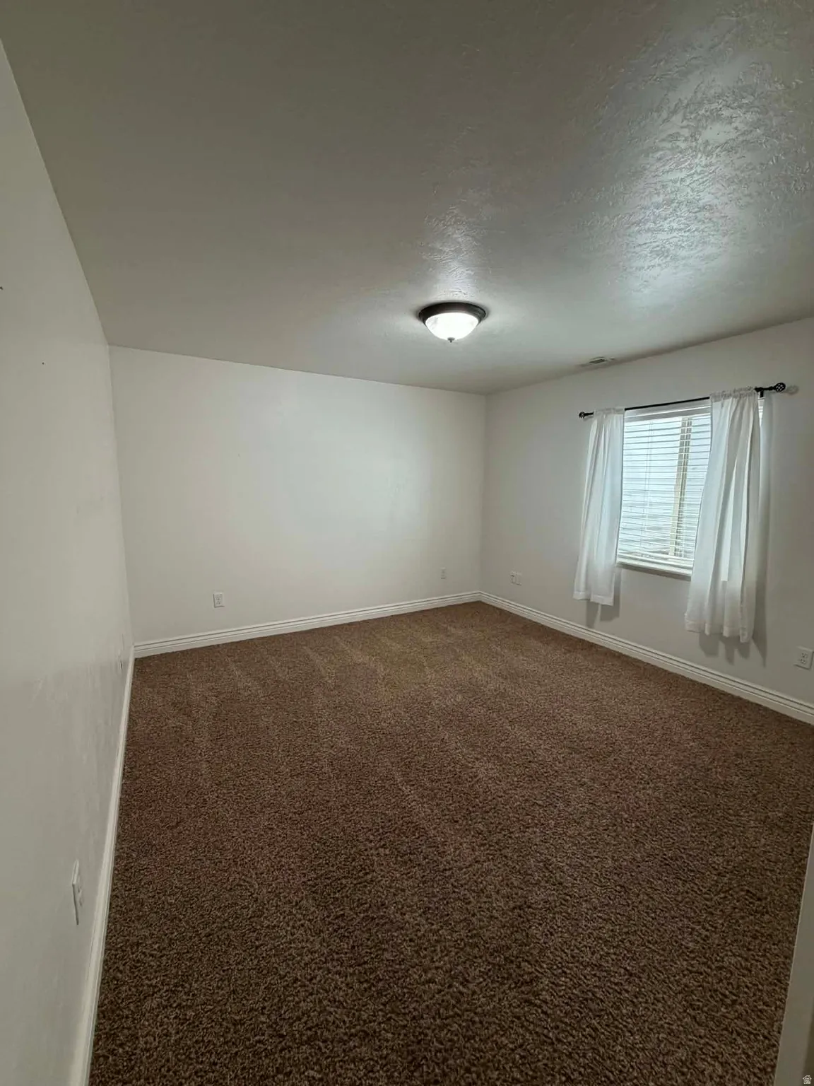 Spare room with dark colored carpet and a textured ceiling