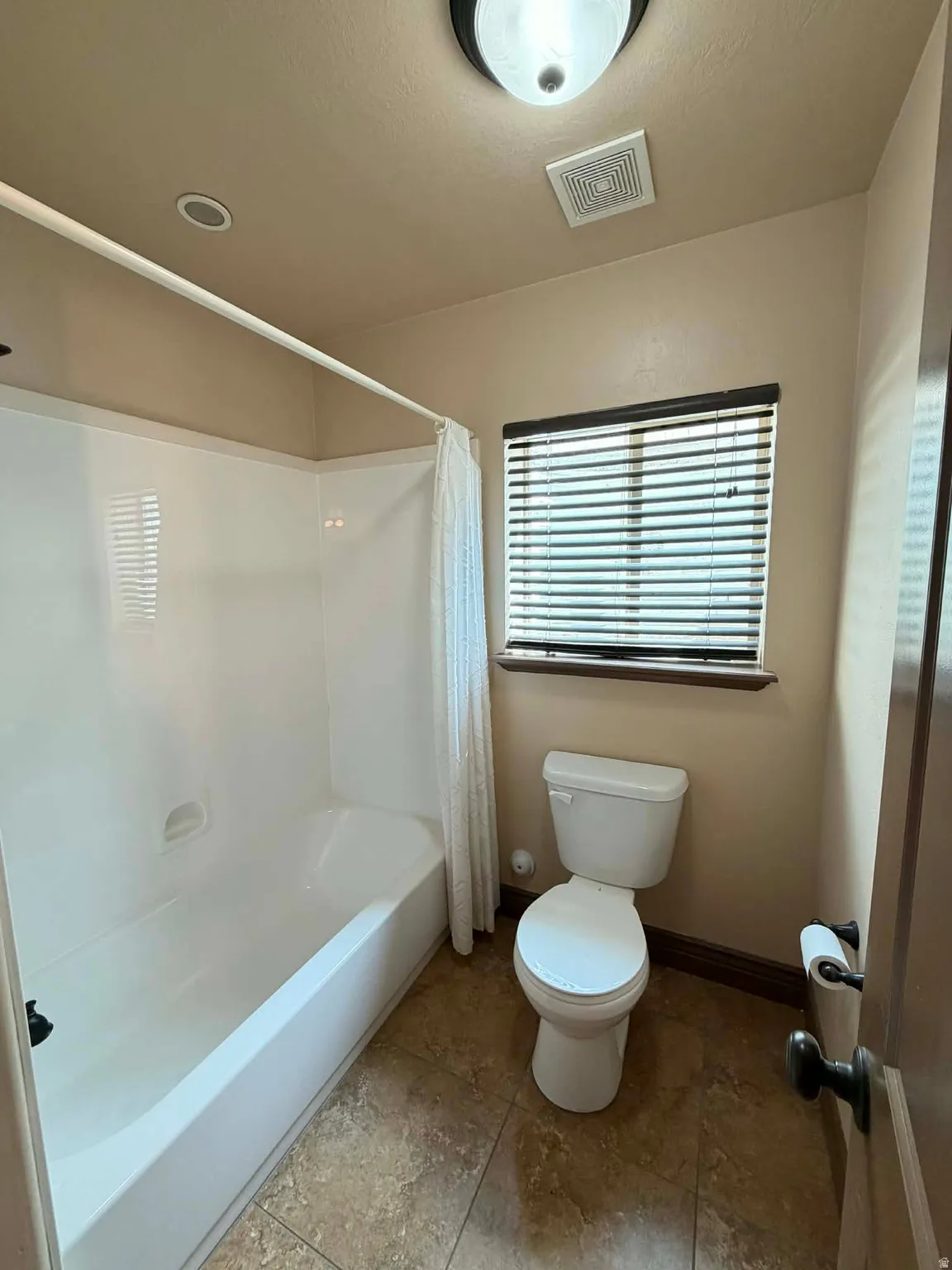 Full bath featuring toilet and shower / bath combination with curtain