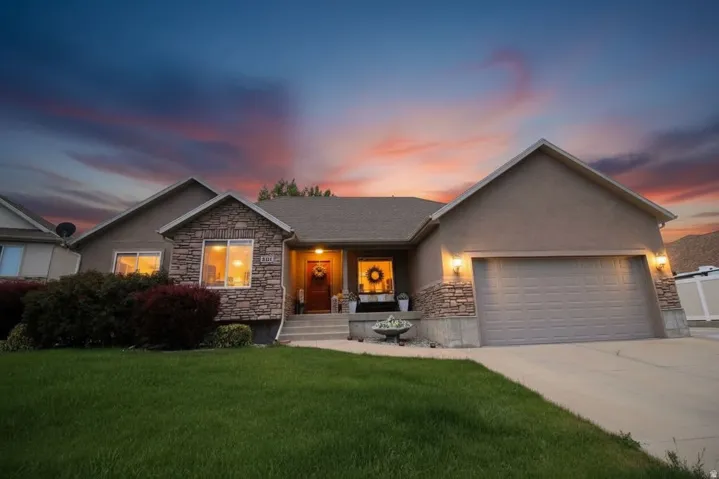 Single-story residence featuring a two-car garage, stone and stucco exterior, and a concrete driveway
