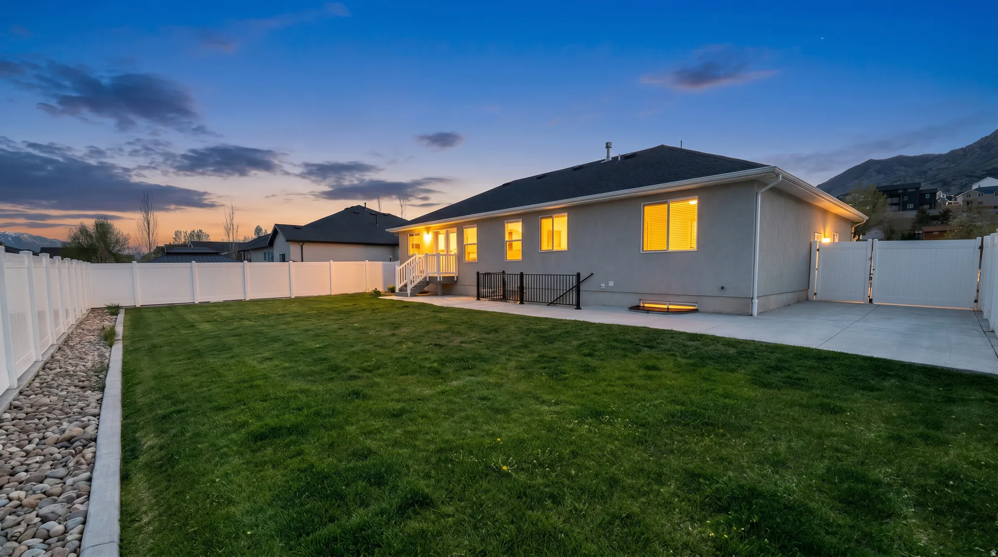 Back of house featuring a fenced backyard, a gate, a patio, and stucco siding