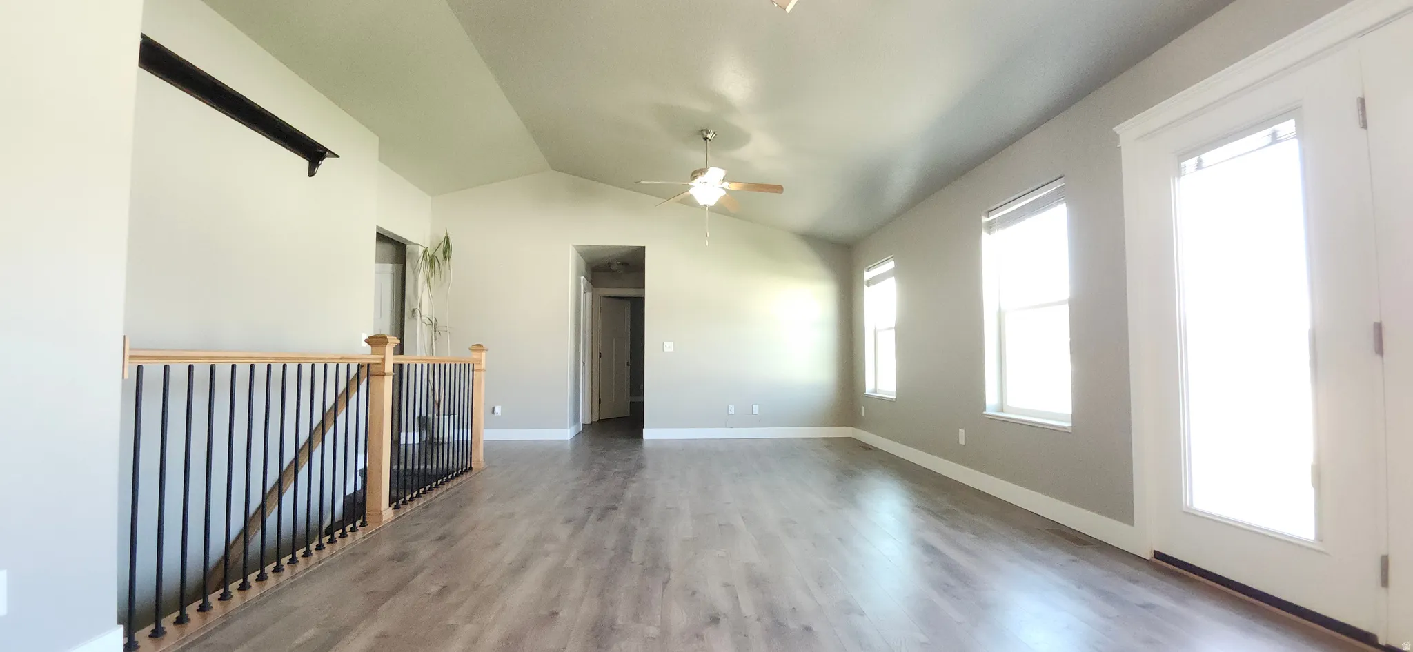 Spare room featuring vaulted ceiling, light wood-style floors, and a ceiling fan