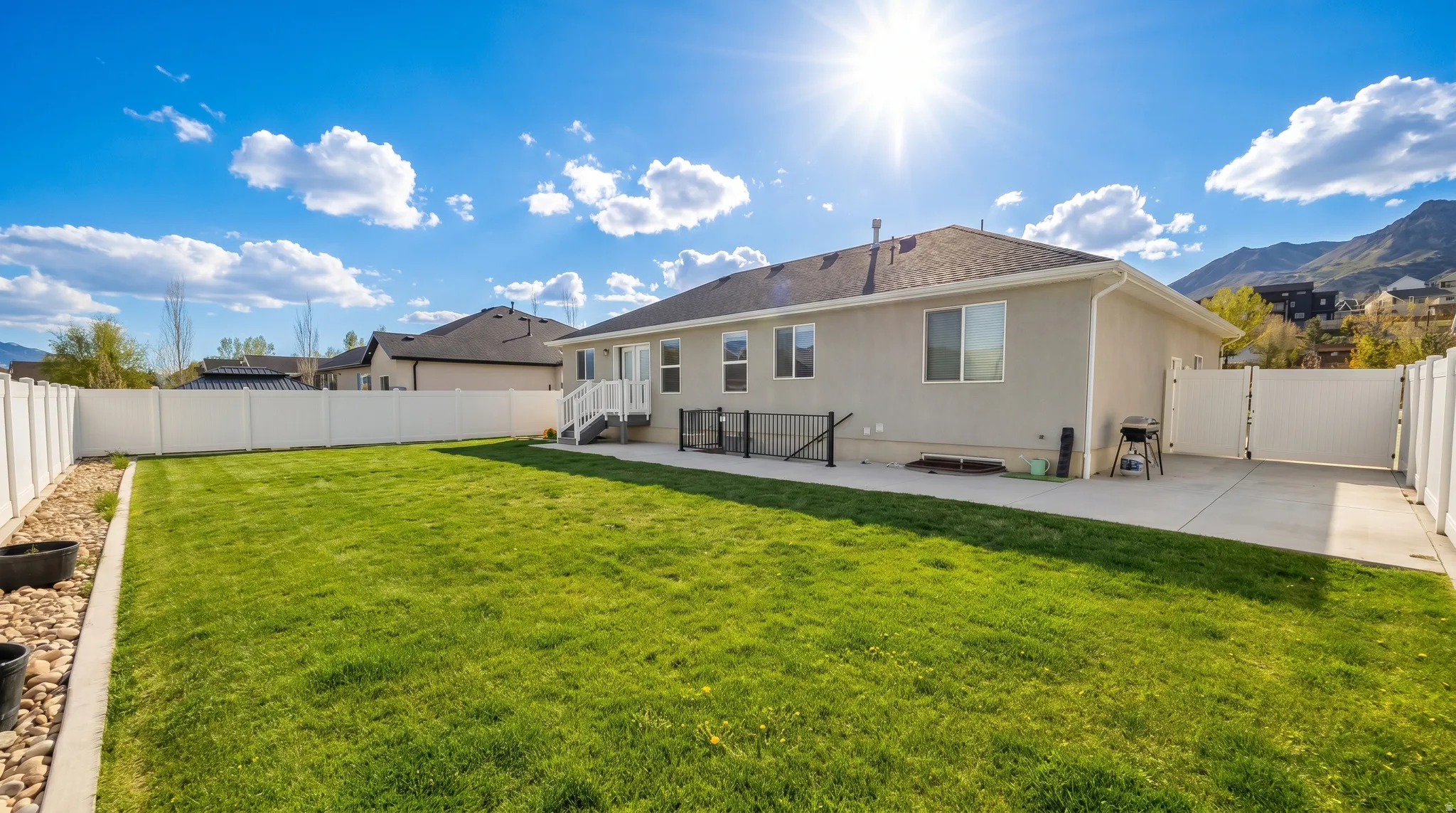 Rear view of house with a gate, a fenced backyard, stucco siding, and a patio area