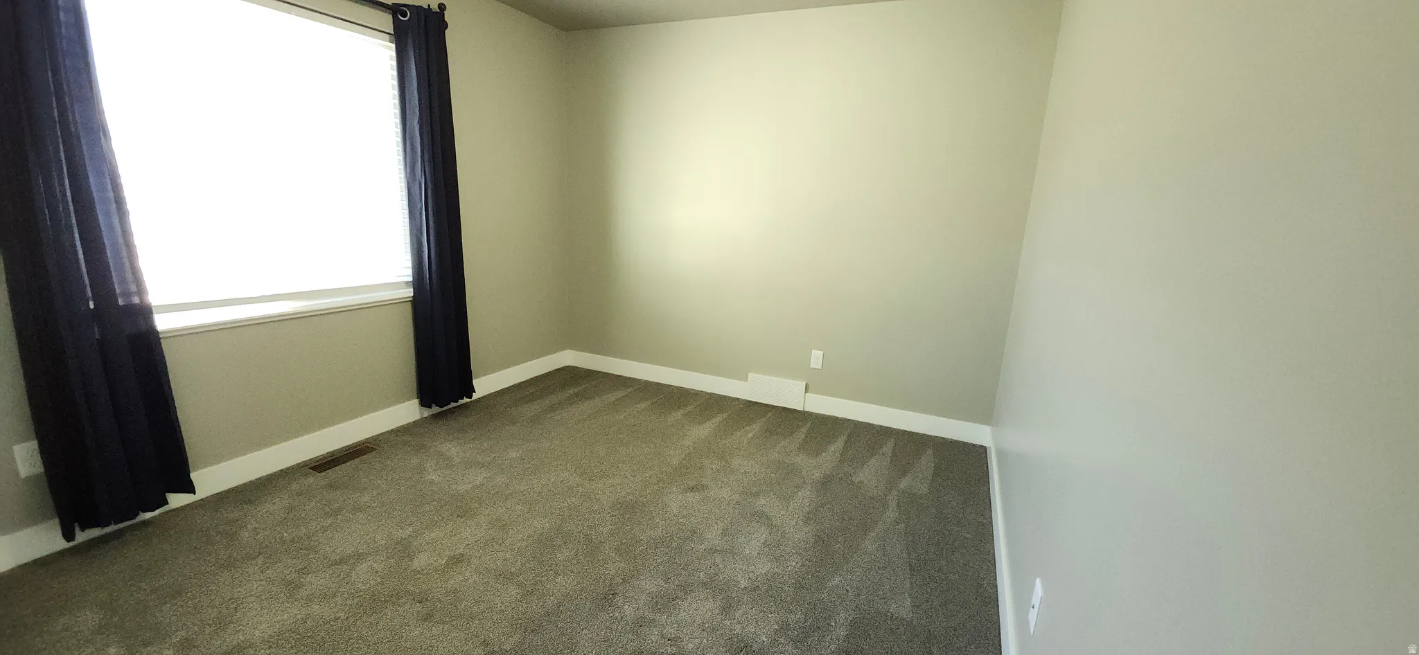 Carpeted spare room with baseboards