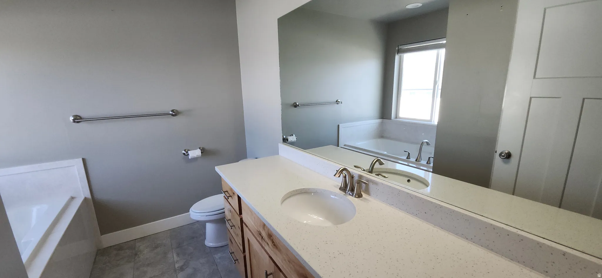 Full bath featuring a bath, vanity, and dark tile patterned floors