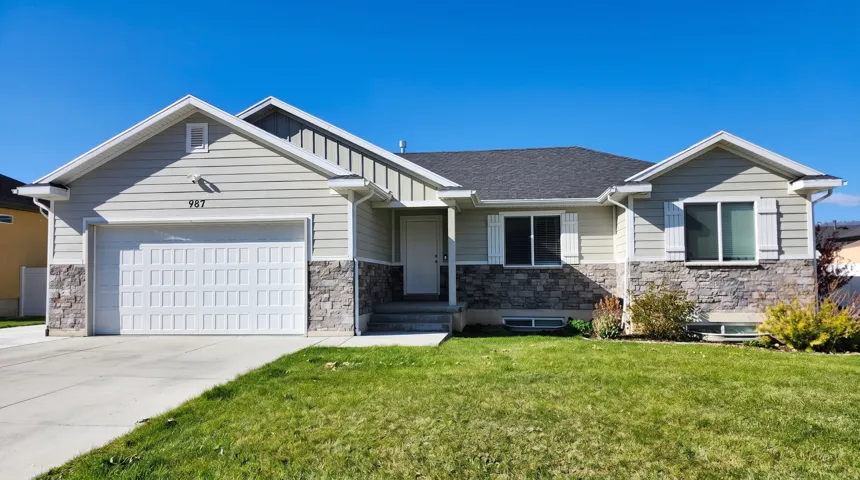 Craftsman house with stone siding, a garage, driveway, a front lawn, and roof with shingles