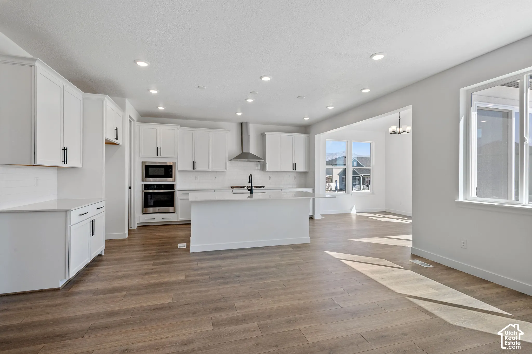 Kitchen featuring white cabinetry, stainless steel appliances, a center island, and wood-finish flooring