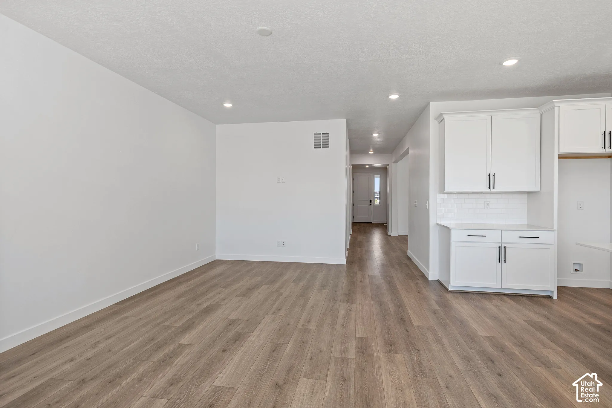 Open-concept living area featuring wood-finish flooring, recessed lighting, and white walls