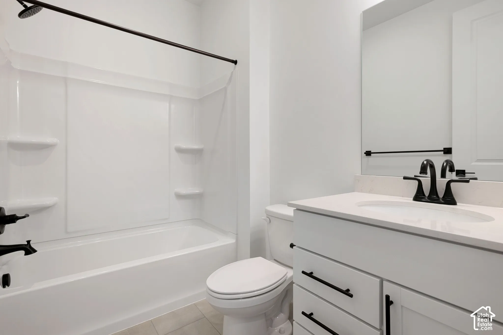Integrated bathtub and shower with white surround, white vanity with stone-finish countertop, undermount sink, and matte black fixtures
