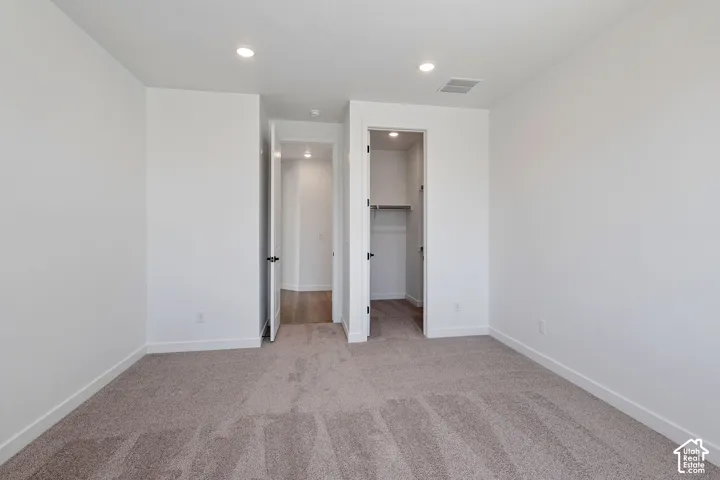 Plush carpet flooring, recessed ceiling lighting, and a built-in closet with shelving