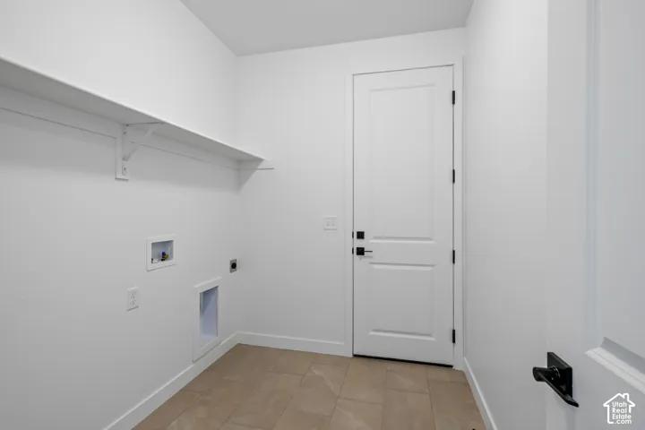 White walls featuring a single built-in shelf, tiled flooring, and a white paneled door with matte black hardware
