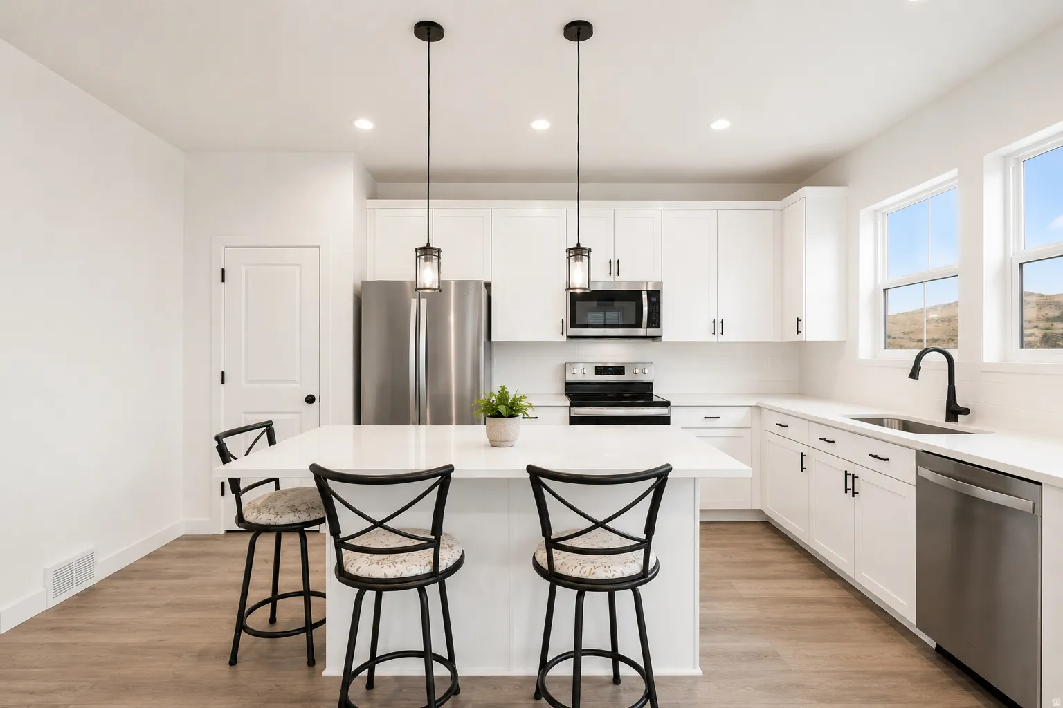 Contemporary kitchen featuring white cabinetry, stainless steel appliances, a center island with pendant lighting, light wood-finish flooring, and bright windows