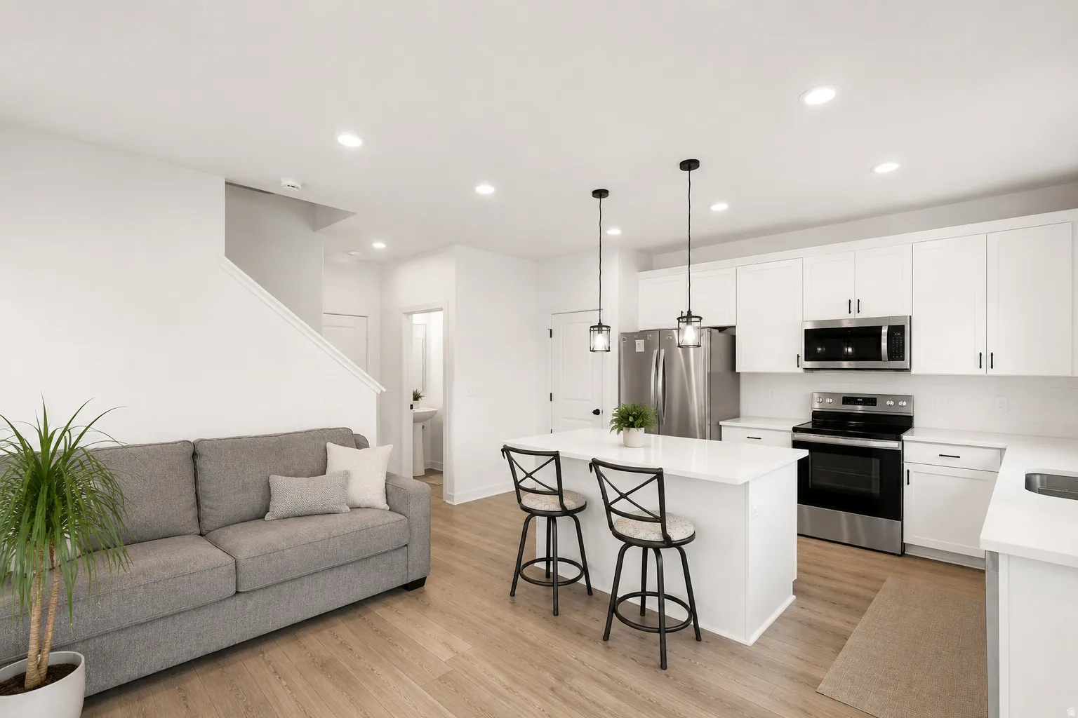 Contemporary kitchen featuring white cabinetry, stainless steel appliances, a center island with pendant lighting, and wood-finish flooring