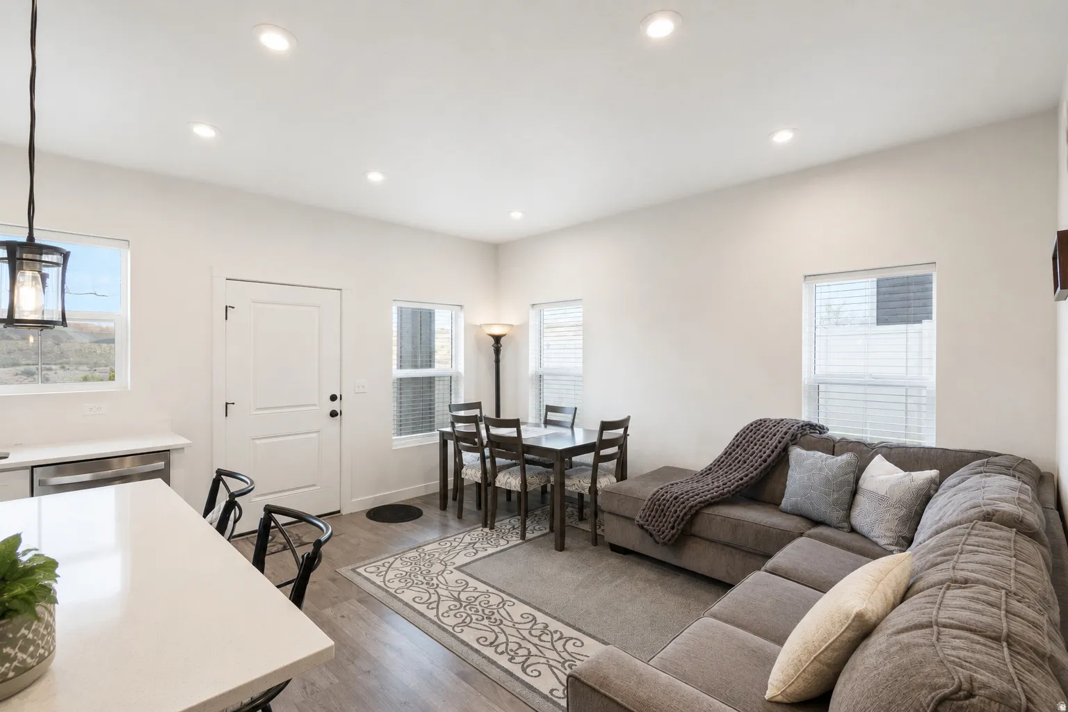 Open-concept living space featuring wood-finish flooring, recessed lighting, and multiple windows