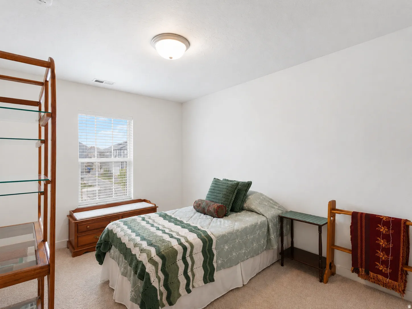 Room featuring neutral wall paint, carpet flooring, a single window with blinds, and a flush-mount ceiling light fixture
