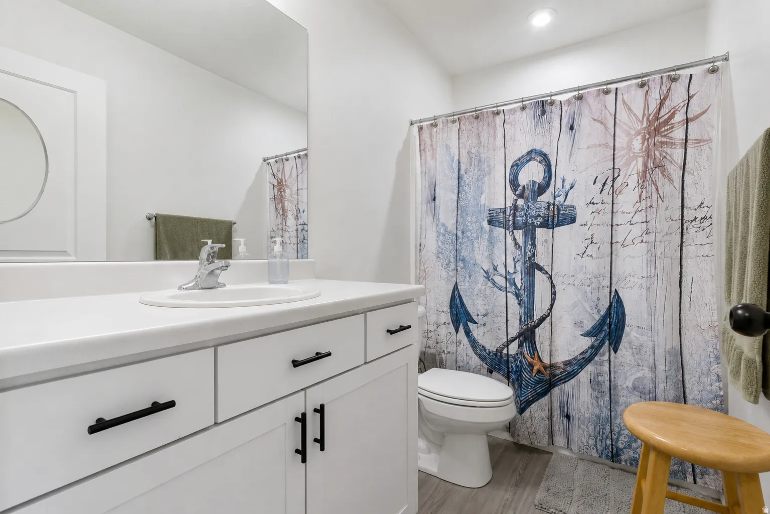 Bathroom featuring a white vanity with an integrated sink, chrome faucet, and black hardware