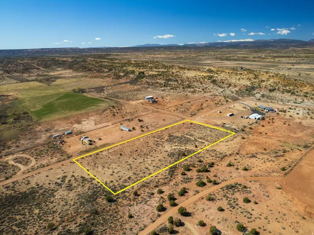 Aerial view of sparsely populated area with property boundaries highlighted and a mountainous background