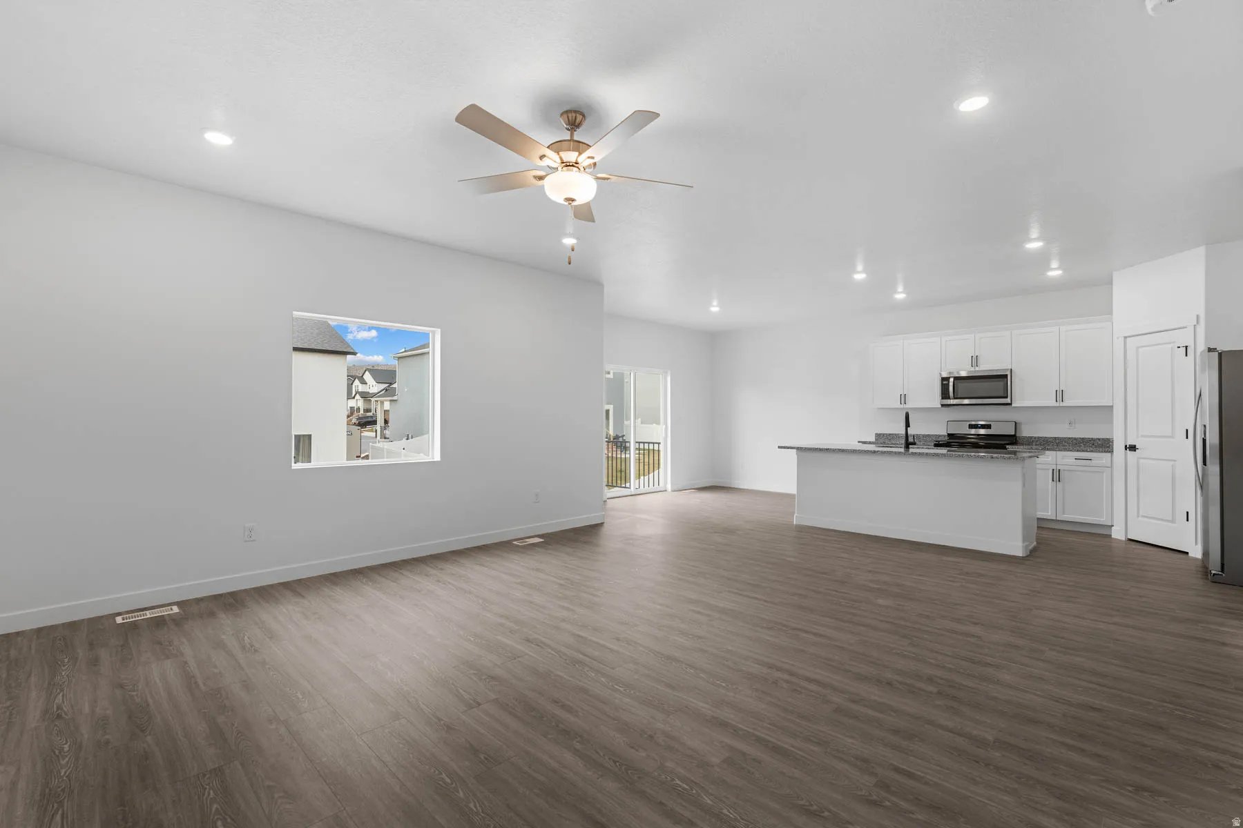 Unfurnished living room with dark wood finished floors, a ceiling fan, and recessed lighting