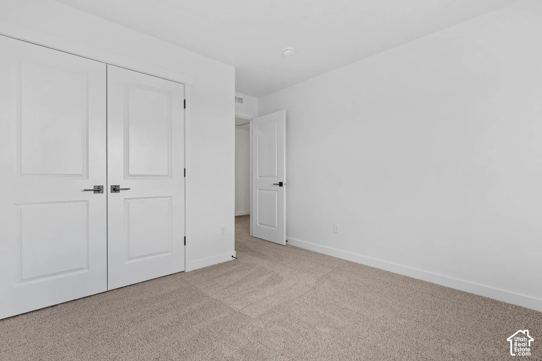 Unfurnished bedroom with light colored carpet and a closet
